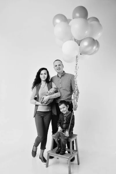 El concepto de celebración, tiempo de diversión - familia en la fiesta. adultos y niños sobre un fondo blanco entre las bolas de colores celebran su cumpleaños — Foto de Stock