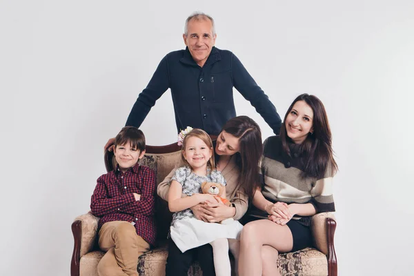 Concepto de infancia feliz, familia, amor - grupo de personas sobre un fondo blanco: adultos y niños con juguetes sentados en el mismo sofá — Foto de Stock