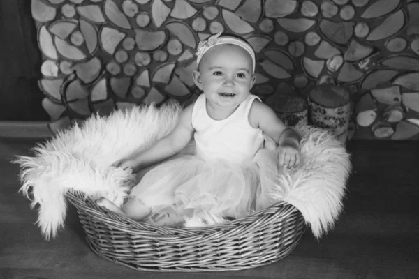 Girl in a dress sitting in a basket on a white firewood. the concept of holiday, fun, home comfort — Stock Photo, Image