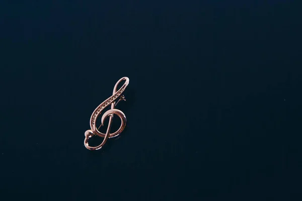 Violino dourado sobre fundo escuro. enfeite: broche. espaço de cópia. O conceito de símbolos musicais, objetos isolados, trabalho de jóias, jóias — Fotografia de Stock