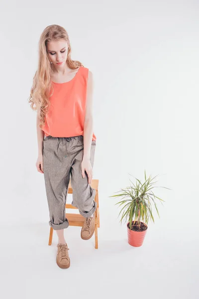 advertising clothes: a girl on a white background. model next decorative element of the interior: a flower in a pot.