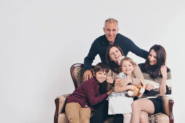 Concepto de infancia feliz, familia, amor - grupo de personas sobre un fondo blanco: adultos y niños con juguetes sentados en el mismo sofá — Foto de Stock