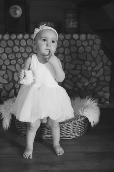 Portrait of a baby biting a finger thoughtfully. a little girl in a light dress. The concept of bad habits, fashion for children, children's day — Stock Photo, Image