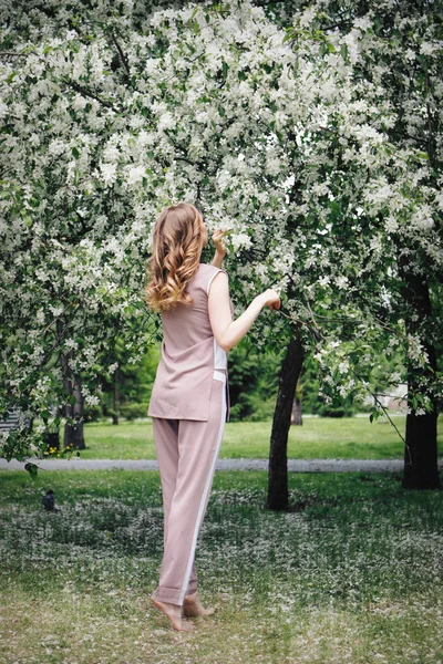 Flicka som går i parken bland blommande träd. Vårhumör-en kvinna i naturen — Stockfoto