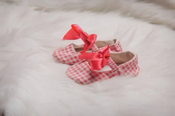 advertising clothes: baby\'s shoes with red bow on a white background.