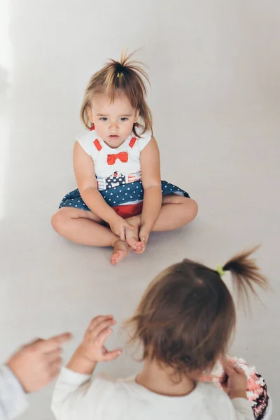 Dos chicas en poses idénticas. Los bebés miran hacia otro lado sorprendidos. Aislado sobre fondo blanco. Copiar espacio — Foto de Stock