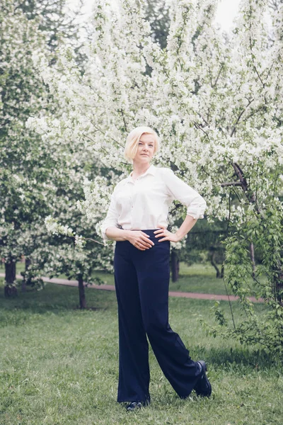 Meisje wandelen in het park tussen de bloeiende bomen. Lente Mood-een vrouw in de natuur — Stockfoto