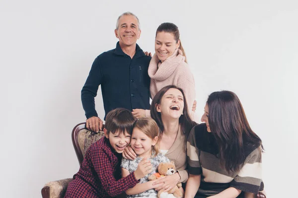 Concept of happy childhood, family, love - group of people on a white background: adults and children with toys sitting on the same couch — Stock Photo, Image