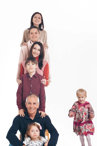 Un groupe de personnes souriantes formait une colonne. Homme heureux parmi les femmes : adultes, enfants. Concept cadeau pour les enfants, journée famille — Photo