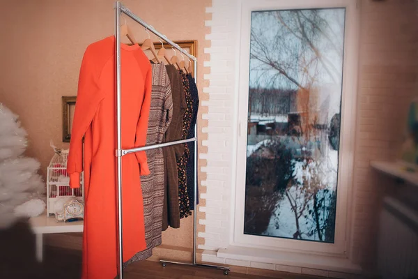 Het concept van maatwerk, kleding voor vrouwen casual stijl, mode, accessoires. Jurken hangend aan een hanger bij het raam — Stockfoto
