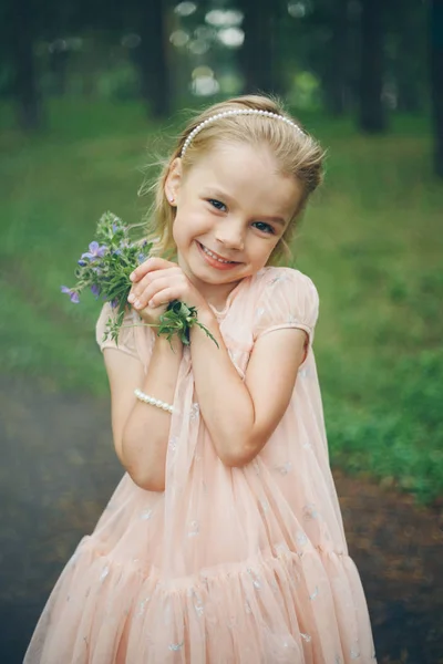 Hermosa chica sosteniendo flores. 8 de marzo: rubia entre flores. El concepto de las felicitaciones, las fiestas femeninas — Foto de Stock