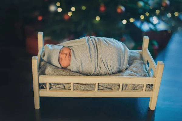 クリスマスツリーを背景にベビーベッドで眠っている帽子の新生児。子宮の中の赤ん坊の模倣。ボースを背景に新生児の肖像画。健康的なライフスタイルのコンセプト, Ivf Christmas, ne — ストック写真