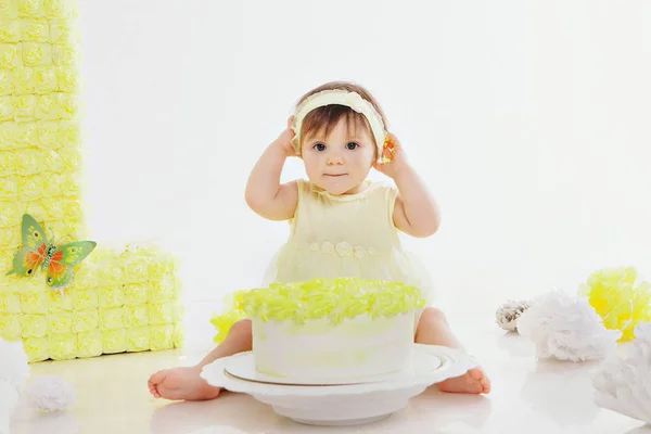 Een klein meisje eet taart met haar handen op de open haard. De baby zat onder het eten. verjaardagsfeestje — Stockfoto