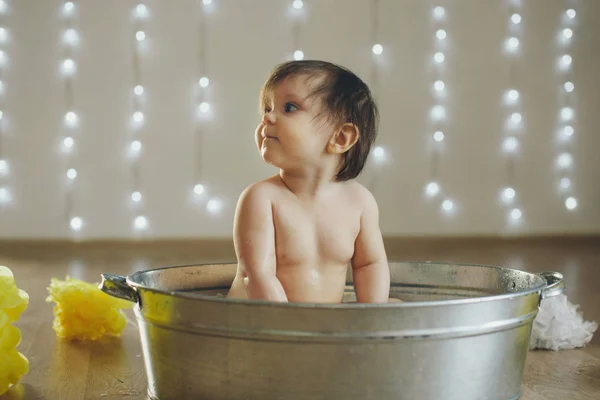 Een klein meisje baadt in een bad met citroen en grapefruit. Een kind wast zich in een bassin tussen gele bloemen. concept van kindertijd, gezondheidszorg, Ivf, hygiëne, citrustherapie — Stockfoto