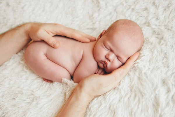 Naked newborn baby lying on the hands of parents on a white background. Imitation of a baby in the womb. beautiful little girl sleeping lying on her stomach. — Stock Photo, Image