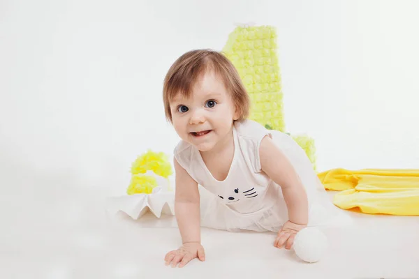 Narozeninová oslava: dívka sedící na podlaze mezi dekoracemi: čísla 1, umělé květiny a bílé koule — Stock fotografie