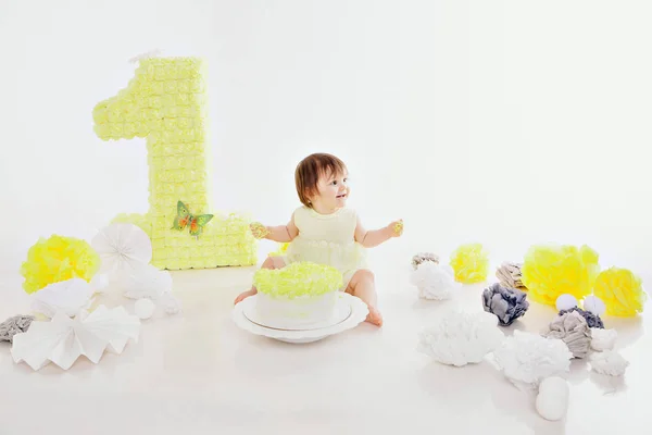 Een klein meisje eet taart met haar handen op de open haard. De baby zat onder het eten. verjaardagsfeestje — Stockfoto