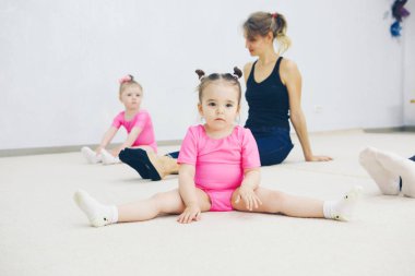 Moskova, 12.10. 2019. Turunçgil fitness kulübündeki çocuklar için kurslar. Küçük bir kız eğlence amaçlı jimnastik yapıyor. Spor egzersizleri ve esneme: atletizm