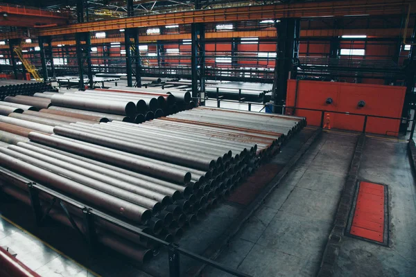 Concepto de la industria pesada, maquinaria de construcción tubos largos de metal dentro de una habitación grande. Materiales de construcción en el hangar — Foto de Stock