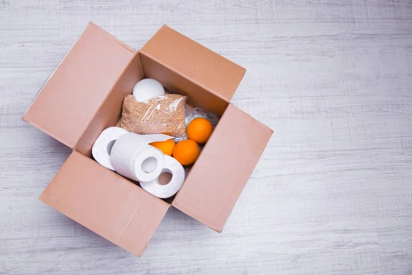 essential products for self-isolation in a box: cereals. toilet paper, fruit, canned food. home delivery. Assistance to population