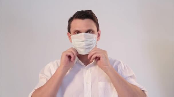 白い背景の男の肖像画で 医療用マスクを着用している 医療機器の実証 男が指差す 隔離の概念 自己分離 コロナウイルスからの保護 ウイルス 病気の恐怖 — ストック動画