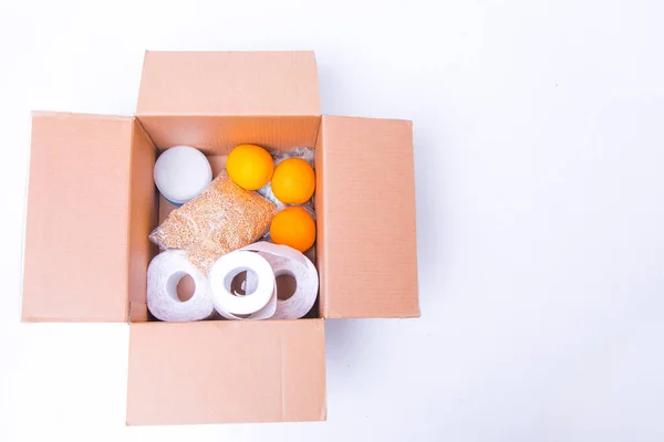 essential products for self-isolation in a box: cereals. toilet paper, fruit, canned food. home delivery. Assistance to population