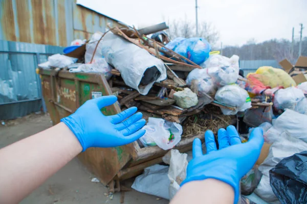 a man in rubber gloves points to a pile of garbage in a container. garbage collapse. Janitors \' strike. environmental disaster of plastic recycling. hand close-up