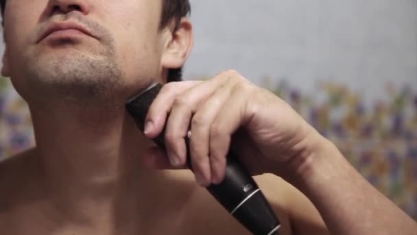 一个人刮胡子 那家伙用电动剃须刀刮胡子 早上在浴室里接受治疗 留胡子特写 复制空间 — 图库视频影像
