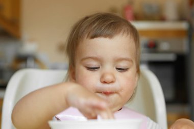 Elleriyle bebek maması yiyen bir çocuğun portresi.