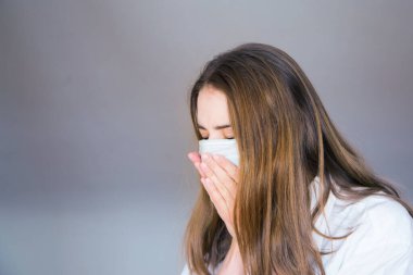 Tıbbi maskeli, beyaz arka planda, tıbbi maskeli bir kadın. Hasta öksürüyor.