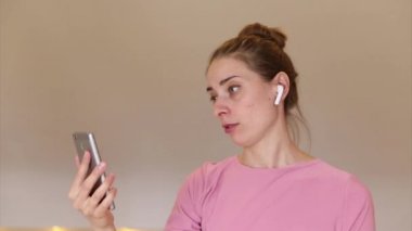 Kız kulağına kablosuz bir kulaklık yerleştiriyor ve telefonda video bağlantısı kullanarak konuşmaya başlıyor. İnsan ve modern teknolojiler