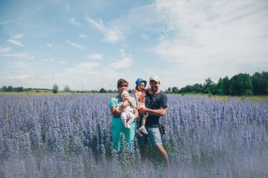 Aile bir çiçek çayırında yürüyor. Bir adam ve bir kız mor çiçeklerin arasında hayatın tadını çıkarıyorlar. Yaz konsepti, sıcaklık, özgürlük ve bahar kokusu.