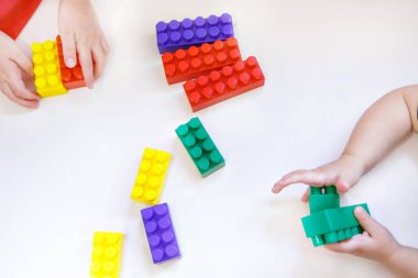 Çocuk, inşaatçının renkli detaylarıyla oynuyor. Elindeki oyuncaklar. İyi motor becerilerin geliştirilmesi, eğitim oyunları, çocukluk, tüp bebek, çocuk günü, anaokulu. Boşluğu kopyala