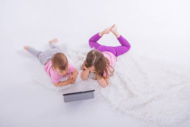 Çocuklar tablette çizgi film izliyorlar. Karantina sırasında kızlar için evde eğitim