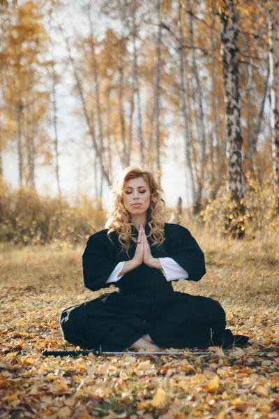 European woman with a katana in a kimono. the girl trains martial arts. a woman in the autumn forest. a warrior with a cold weapon in his hands