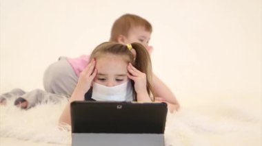 Salgın: tıbbi maskeli bir çocuğun uzaktan öğrenmesi. Hasta bir kız arkasında dizüstü bilgisayar bırakmış.