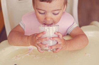 Bardaktan yoğurt içen bir çocuğun portresi. Yüzüne yemek bulaşmış.
