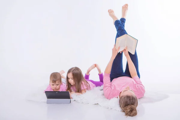 a woman reads a book, children watch a cartoon on a tablet. Hobbies and recreation with gadgets. Family vacation, spend time together. home schooling