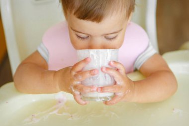 Bardaktan yoğurt içen bir çocuğun portresi. Yüzüne yemek bulaşmış.