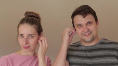 Bir adam ve bir kız kablosuz kulaklık kullanarak müzik dinliyorlar. İnsan ve modern teknolojiler.