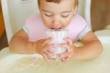 Bardaktan yoğurt içen bir çocuğun portresi. Yüzüne yemek bulaşmış.