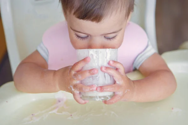 ガラスからヨーグルトを飲む子供の肖像画です 食べ物で顔を汚し — ストック写真