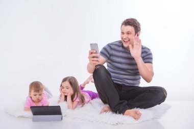 Gündelik hayatta modern teknolojiler: bir adam telefonda kulaklıkla konuşur, çocuklar tablet üzerinde çizgi film izler. Aletlerle hobiler ve eğlence. Ebeveynler ve kızlar yerde.