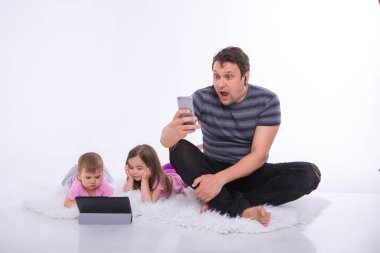 Gündelik hayatta modern teknolojiler: bir adam telefonda kulaklıkla konuşur, çocuklar tablet üzerinde çizgi film izler. Aletlerle hobiler ve eğlence. Ebeveynler ve kızlar yerde.