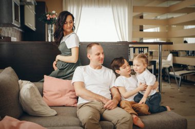 İki çocuklu bir aile kanepede oturuyor. Hafta sonu evde. Birlikte vakit geçirmek.