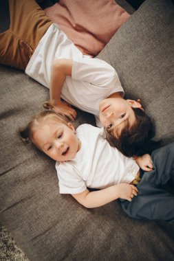 Çocuklar birlikte oynuyorlar. Mutlu çocuklar: erkek ve kız kardeş yerde yatıyor.