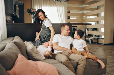 İki çocuklu bir aile kanepede oturuyor. Hafta sonu evde. Birlikte vakit geçirmek.