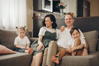 İki çocuklu bir aile kanepede oturuyor. Hafta sonu evde. Birlikte vakit geçirmek.