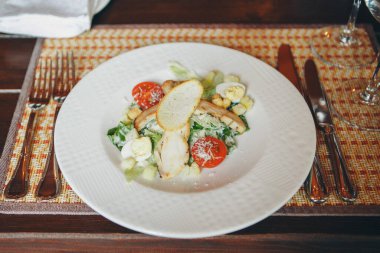 Kızarmış chiken, bıldırcın yumurtası, marul yaprağı, tost, parmesan, domates ve krema soslu klasik Sezar salatası servis edilen masaya yakın. İtalyan mutfağı