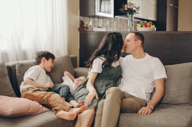 İki çocuklu bir aile kanepede oturuyor. Hafta sonu evde. Birlikte vakit geçirmek.